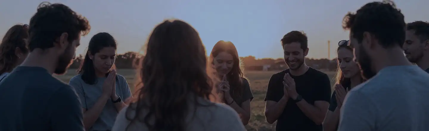 A group of people praying together at sunset