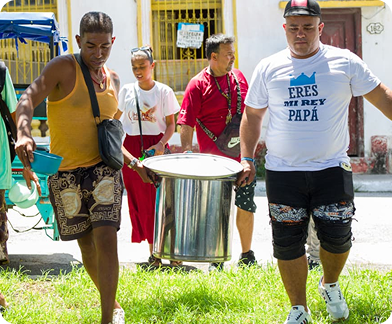Two men carrying a large metal pot